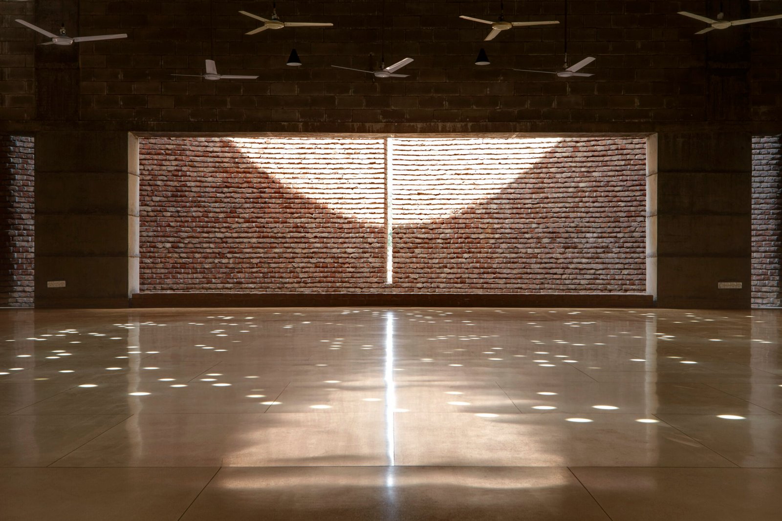 Circular roof openings cast constellations of light across the polished floor of the Bait Ur Rouf Mosque prayer hall in Dhaka
